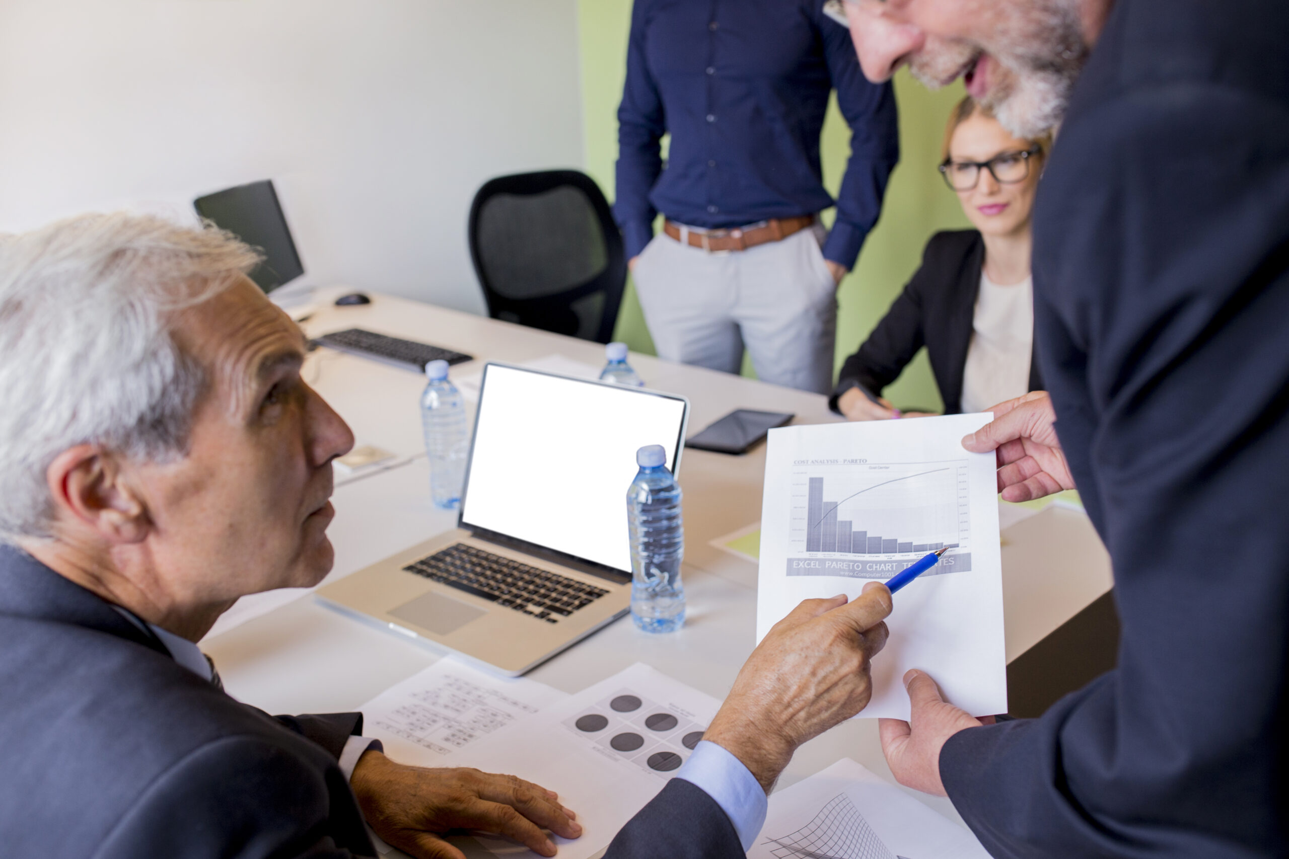 Team meeting with financial documents and marketing reports visible